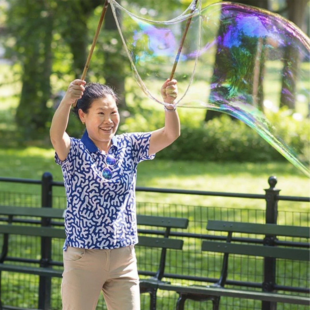 Handcrafted from real wood — BubbleStix giant bubble sticks in use A woman lifting hardwood BubbleStix to make a giant bubble in the park