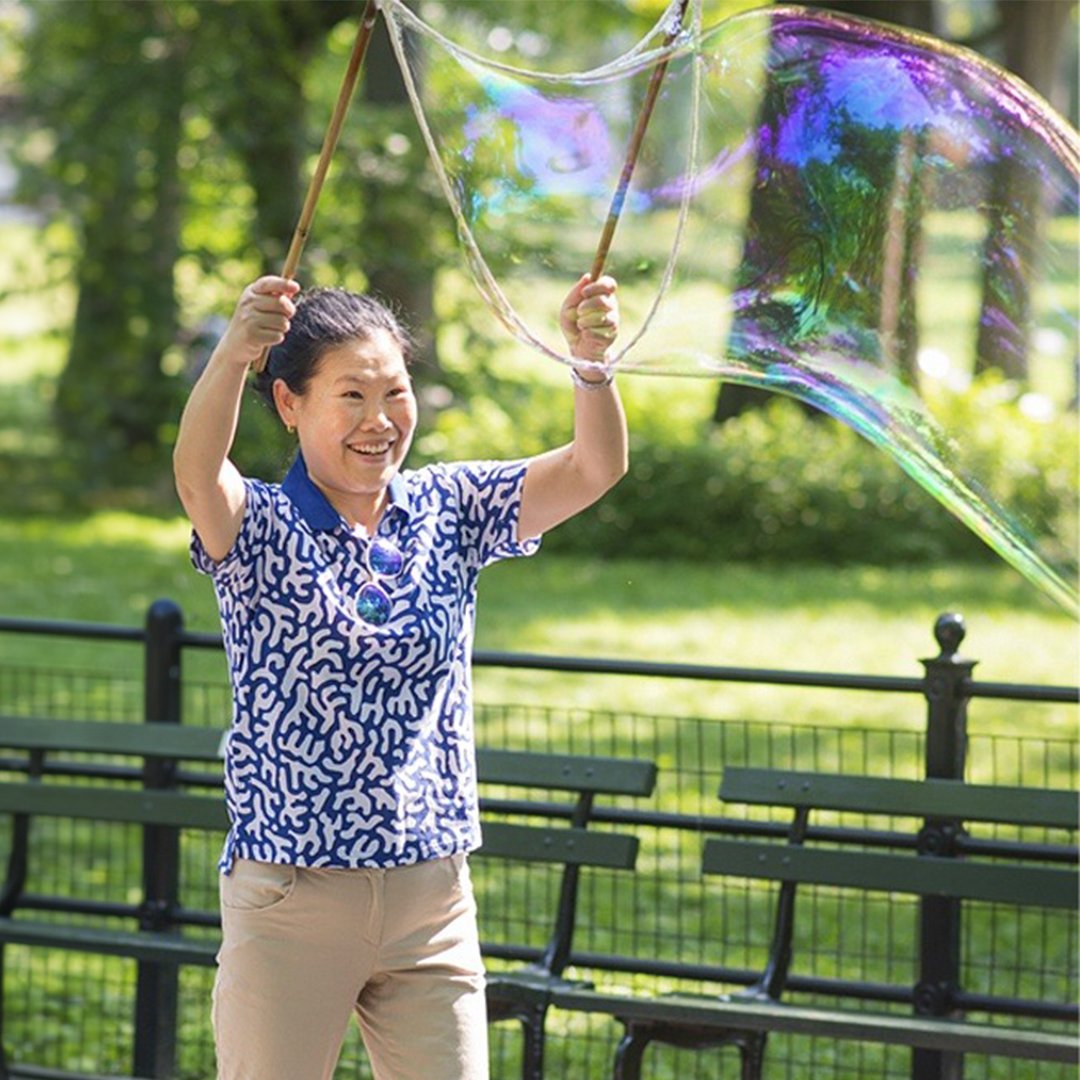 Smiling woman making a giant bubble in a green park