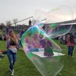 Giant bubble floating across a crowded festival lawn during a BubbleStix group bubble activity