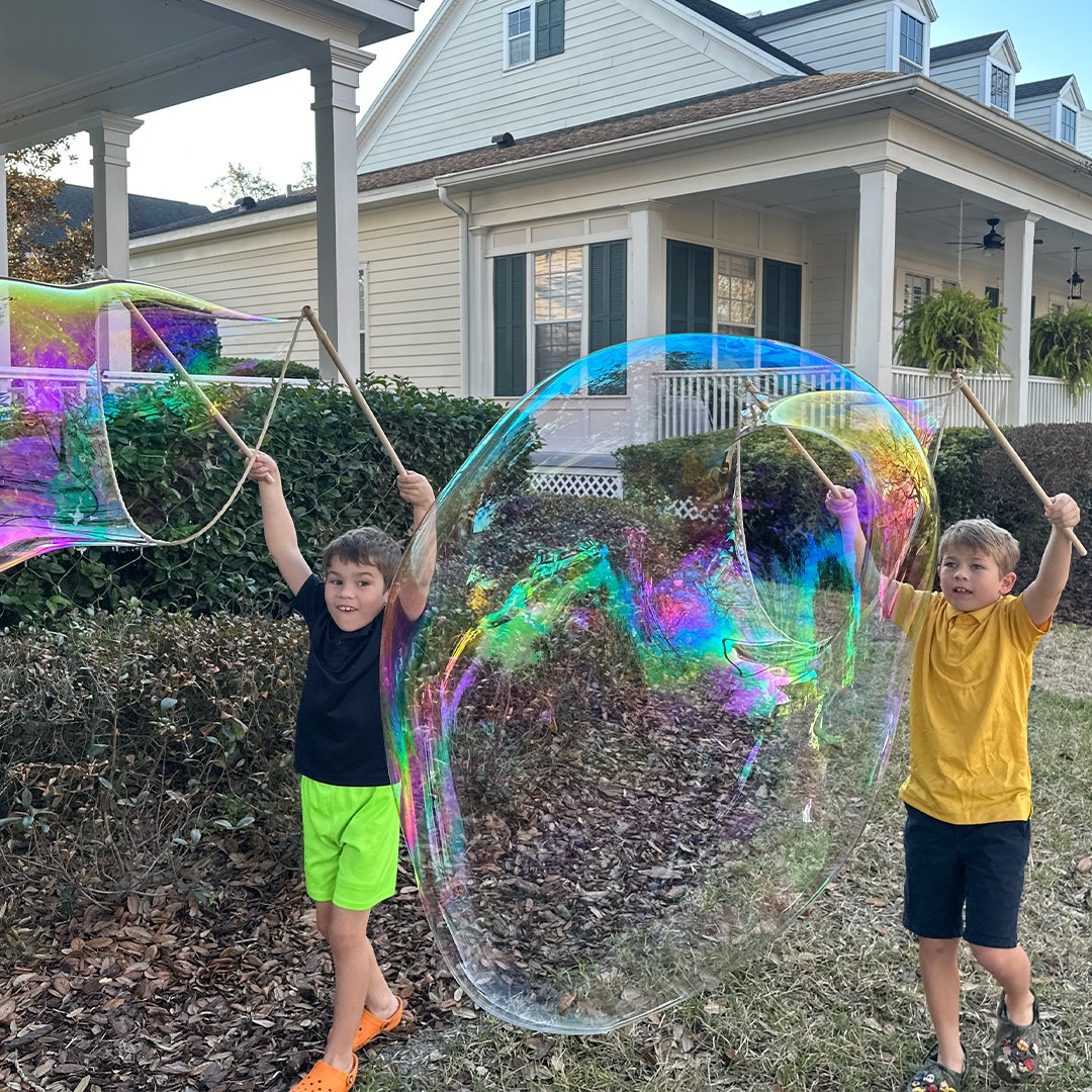 Two boys making a giant bubble together with BubbleStix